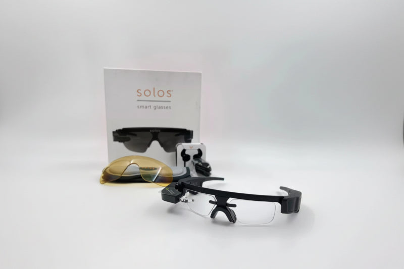 Black smart glasses with a clear lens on a white background, featuring the 'solos' brand.